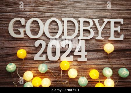 Lettre à l'alphabet Au revoir 2024 avec boule en coton, décoration LED sur fond de bois Banque D'Images