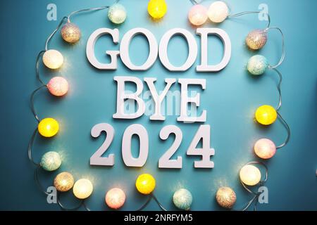 Lettre à l'alphabet Au revoir 2024 avec boule en coton, décoration LED sur fond bleu Banque D'Images