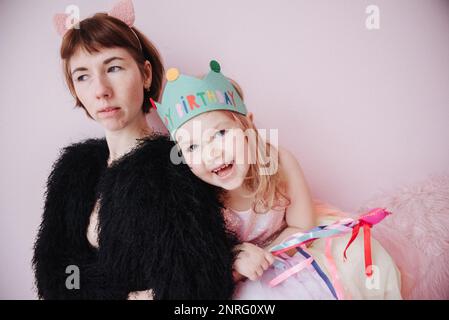 fille dans une robe rose avec sa mère sur un fond rose Banque D'Images