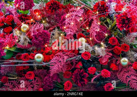 Arrangement de fleurs artificielles colorées et boules de noël avec chaîne lumineuse de lumières Banque D'Images