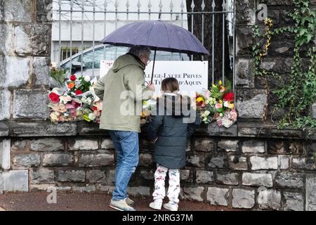 Les parents d'élèves et d'enfants viennent déposer des fleurs en hommage à l'enseignant assassiné devant le collège privé Lycée de Saint Thomas d'Aquin à Saint Jean de Luz. 23 février 2023. Une enseignante espagnole au lycée Saint-Thomas-d'Aquin de Saint-Jean-de-Luz, Pyrénées-Atlantiques, est décédée après avoir été poignardée en classe par un étudiant de sa classe mercredi 22 février. L'étudiant de 16 ans du secondaire accusé de l'assassinat a déclaré en garde à vue avoir entendu des voix lui demandant de tuer son professeur, l'expert psychiatre qui l'a examiné le considérait responsable Banque D'Images