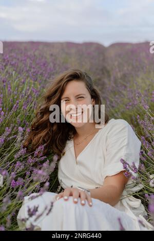 Femme assise parmi les fleurs dans un champ de lavande anglais Banque D'Images