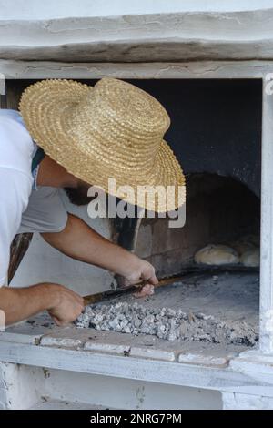 Le boulanger prépare la pâte pour cuire du pain dans un four rural. Village ukrainien Banque D'Images