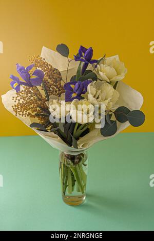Bouquet de fleurs de printemps. Iris, tulipes, mimosa et eucalyptus. Fleur jaune et bleue. Gros plan sur les boutons. Fond floral. Iris violet, double tulipe blanche. Cadeau. Humeur du mois de mars. Banque D'Images