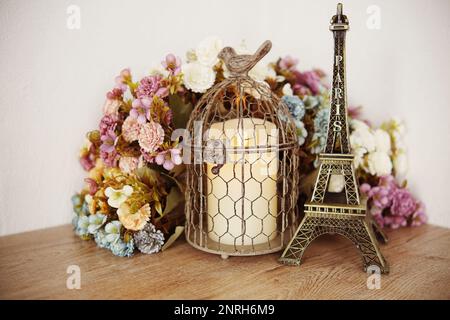 Décoration maison Tour Eiffel, bougie LED et fleur artificielle sur fond de baie en bois Banque D'Images