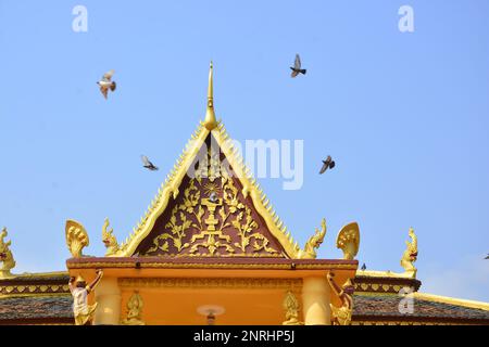 Les pigeons encadrent le toit doré de la pagode baignée dans la lumière du matin à Phnom Penh, au Cambodge Banque D'Images