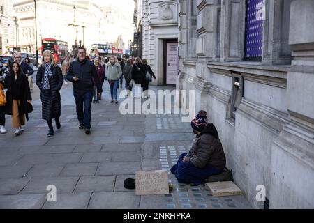 Un homme sans abri est assis sur le trottoir avec un panneau demandant de l'aide pour la nourriture ou l'argent, Piccadilly, Londres, Angleterre, Royaume-Uni Banque D'Images