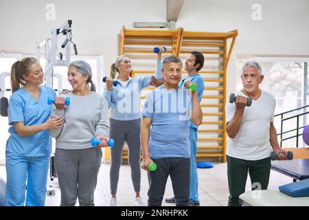 Physiothérapeutes aidant les hommes et les femmes âgés à faire de l'exercice au centre de réadaptation Banque D'Images