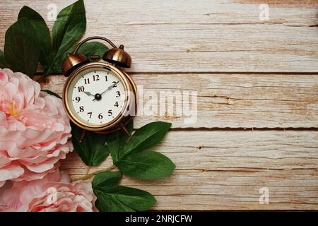 Réveil avec cadre de fleurs de pivoine rose sur fond de bois Banque D'Images