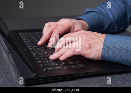 Les mains d'un homme d'affaires mature qui tape rapidement sur le clavier de son ordinateur portable Banque D'Images