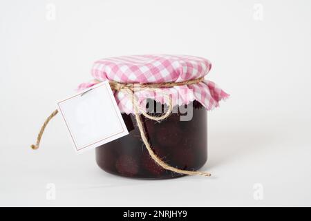 Pot de confiture de fraises maison avec étiquette vide isolée sur fond blanc Banque D'Images