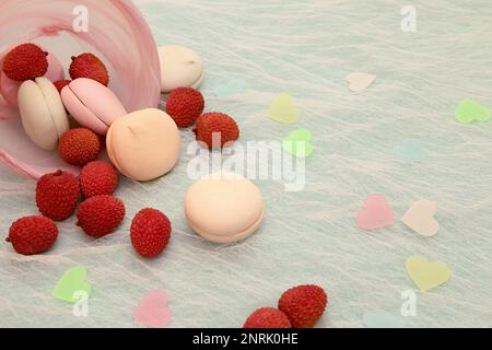 Cette image douce et festive présente un bol rose de pâtisseries variées sur une table blanche Banque D'Images