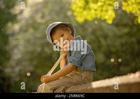 Enfant élégamment habillé, garçon avec chien d'animal, jouant dans le parc sur la flûte, appréciant sa compagnie d'ami d'animal de compagnie Banque D'Images