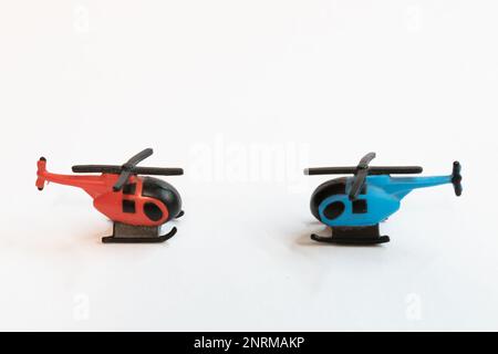 Un gros plan de deux miniatures d'hélicoptère colorées isolées sur une surface blanche Banque D'Images