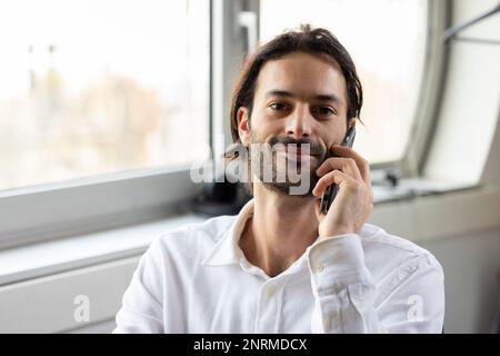 portrait d'un jeune homme d'affaires ou d'un employé de bureau travaillant sur son ordinateur portable dans un bureau confortable et communiquant sur son téléphone mobile Banque D'Images
