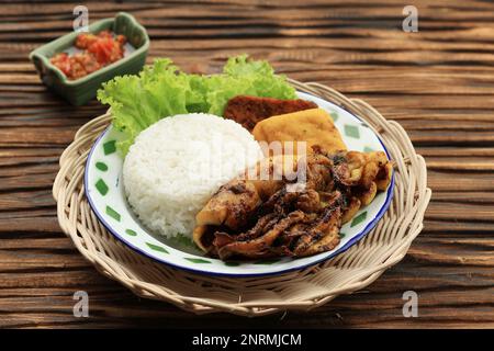 Bakar Cumi de Squid rôti avec riz blanc, Tahu et tempeh. Nasi Penyetan Cumi, servi avec Sambal sur une table en bois Banque D'Images