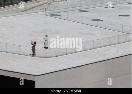 Deux invités prennent des photos du paysage urbain depuis le toit du terminal de croisière Santa Apolonia de Lisbonne, en avril 2022. Banque D'Images