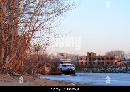 Le navire se dresse une montagne de déchets, un paquet de bouteilles en verre et en plastique se trouve sur la rive de la rivière de la ville au printemps en Russie. Banque D'Images