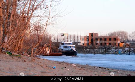 Le navire se dresse une montagne de déchets, un paquet de bouteilles en verre et en plastique se trouve sur la rive de la rivière de la ville au printemps en Russie. Banque D'Images