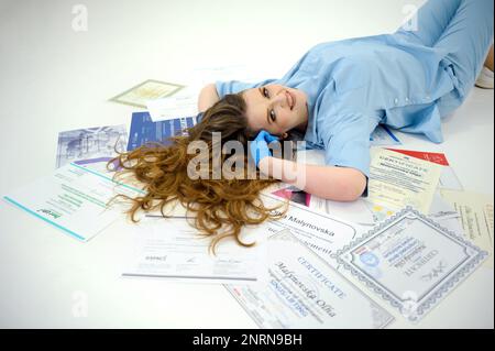 belle femme médecin en gants et bleu costume médical se trouve sur les diplômes certificats sur le plancher blanc formation médicale cours de formation médecin infirmière dentiste stomatologie haute qualification Banque D'Images