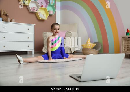 Mignonne petite fille se réchauffant avant le cours de danse en ligne à la maison Banque D'Images