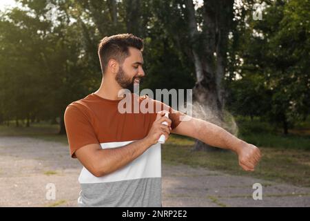 Homme appliquant un insectifuge sur le bras dans le parc. Prévention des piqûres de tiques Banque D'Images