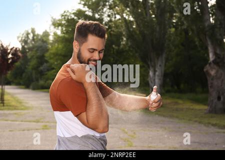 Homme appliquant un insectifuge sur le bras dans le parc. Prévention des piqûres de tiques Banque D'Images