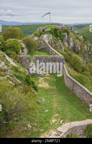 Éditorial : KNIN, DALMATIE, CROATIE, 28 SEPTEMBRE 2022 - le drapeau croate survolant la forteresse de Knin à côté de la statue de Franjo Tudjman qui dirige Banque D'Images