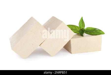 Blocs de délicieux tofu cru au basilic sur fond blanc Banque D'Images