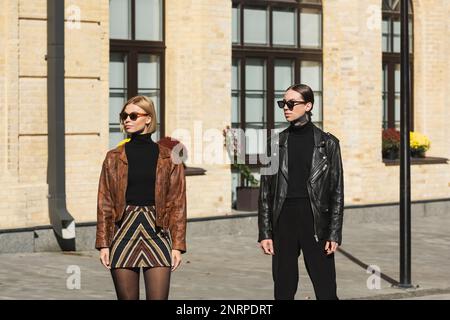 jeune couple élégant en cuir vestes et lunettes de soleil debout sur la rue urbaine, image de stock Banque D'Images