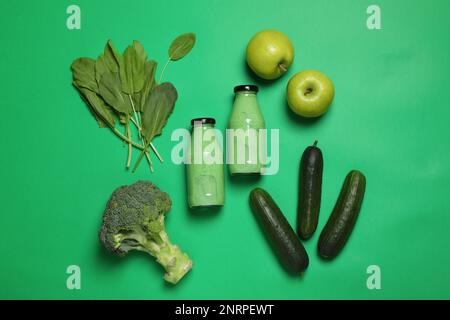 Bouteilles de délicieux smoothie et ingrédients sur fond vert, plat Banque D'Images