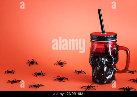 Cocktail d'Halloween dans le crâne de goblet sur fond orange près des araignées. Table de décoration des fêtes. Fête d'Halloween. Copier l'espace pour le texte Banque D'Images