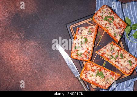 Pizza à la baguette faite maison. Bateaux à baguette. Cocotte chaude avec bacon, champignons, tomates, fromage mozzarella de poulet Banque D'Images