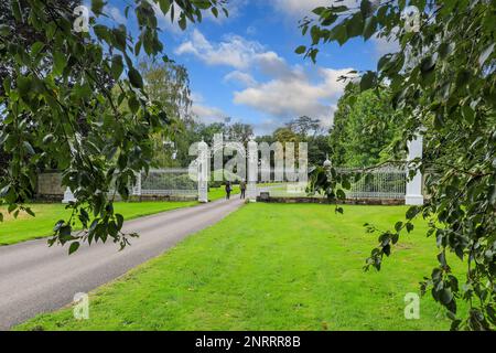 Un chemin à travers les jardins menant à des portes ornées à Cholmondeley Castle Gardens maison de campagne Cholmondeley, Cheshire, Angleterre, Royaume-Uni Banque D'Images