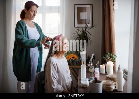 Aide-soignant aidant sa cliente avec une coiffure. Banque D'Images