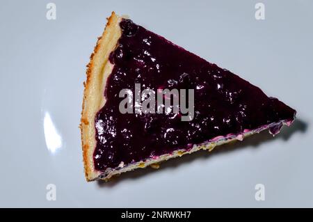 tranche de cheesecake maison recouverte de confiture de myrtilles sur une assiette blanche Banque D'Images