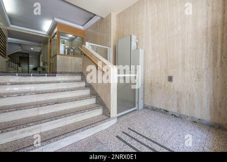 Portail d'un bâtiment résidentiel avec des escaliers en marbre et un ascenseur hydraulique pour les personnes ayant des problèmes de mobilité Banque D'Images