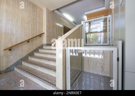 Portail d'un bâtiment résidentiel avec des escaliers en granit, des murs en marbre et un ascenseur hydraulique pour les personnes ayant des problèmes de mobilité Banque D'Images