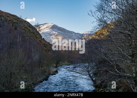 En regardant vers le sud le long d'Afon Glasyn depuis Llyn Dinas, près de Beddgelert, au nord du pays de Galles vers les arbres et les collines de Snowdonia sud. par une belle journée d'hiver. Banque D'Images