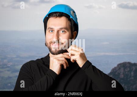 Homme, touriste, grimpeur. Il met un casque, un casque de protection. Dans les montagnes. Hauteur. Banque D'Images
