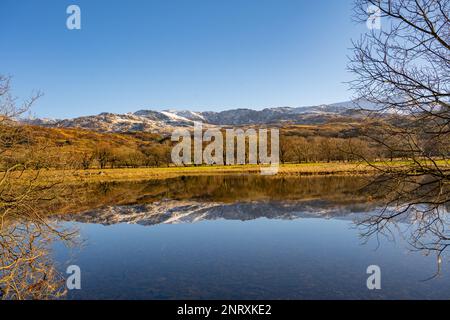 En regardant vers l'est, à travers Llyn Dinas, près de Beddgelert, au nord du pays de Galles vers les arbres et les collines de Snowdonia sud. par une belle journée d'hiver. Banque D'Images