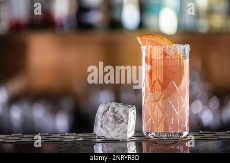 Cocktail Paloma avec tequila garni de pamplemousse sur le comptoir du bar, un cube de glace a conduit la boisson. Banque D'Images