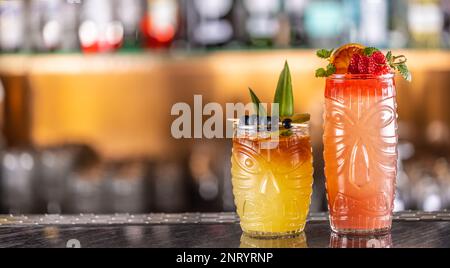 Cocktails mai tai dans des verres hawaïens garnis d'ananas, de bleuets et de fraises sur le comptoir du bar. Banque D'Images