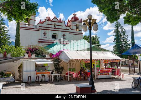 Les gens mangent dans des stands de nourriture en plein air sur la place centrale en face de l'église de Santiago Apostal à Santiago Matatlan, Mexique. Banque D'Images