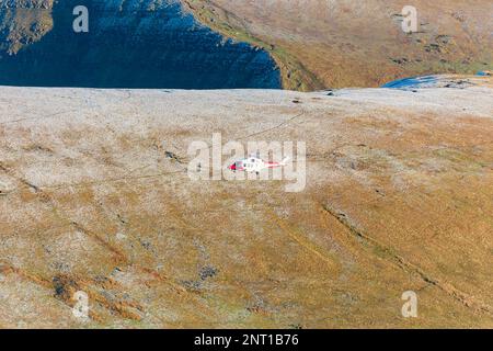 PEN-Y-FAN, PAYS DE GALLES - DÉCEMBRE 12 2022 : hélicoptère de recherche et de sauvetage HM Coastguard fonctionnant au-dessus d'un Pen y-Fan enneigé dans les Brecon Beacons, pays de Galles Banque D'Images