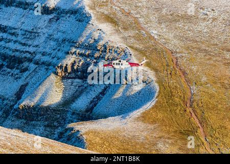 PEN-Y-FAN, PAYS DE GALLES - DÉCEMBRE 12 2022 : hélicoptère de recherche et de sauvetage HM Coastguard fonctionnant au-dessus d'un Pen y-Fan enneigé dans les Brecon Beacons, pays de Galles Banque D'Images