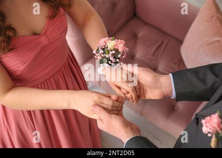 Jeune femme avec la fleur en relief et sa date de bal tenant les mains, gros plan Banque D'Images