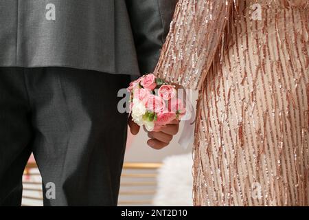 Jeune femme avec la fleur en relief et sa date de bal tenant les mains, gros plan Banque D'Images