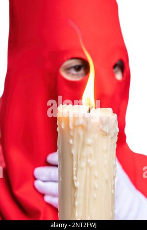 La bougie en flamme d'un jeune Nazaréen avec une cagoule rouge faisant sa station de pénitence dans la procession de la semaine Sainte. Mise au point sélective avec flamme seulement Banque D'Images