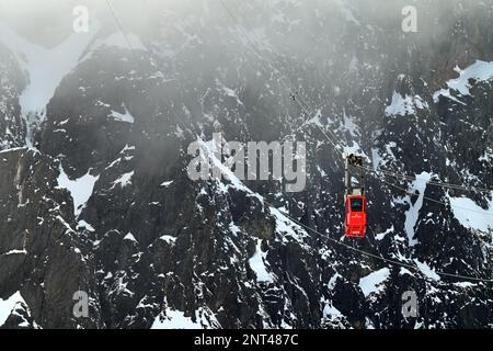 Téléphérique rouge Lomnický štít montant la falaise de montagne dans les Hautes Tatras au-dessus de Skalnaté Pleso et Tatranská Lomnica en hiver Banque D'Images